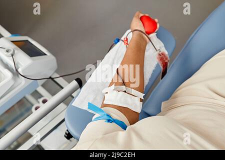Draufsicht Nahaufnahme einer jungen Frau, die Blut spendet und den roten Squeeze Ball hält, Kopierraum Stockfoto