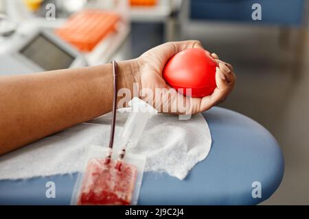 Nahaufnahme einer nicht erkennbaren jungen Frau, die Blut spendet und den roten Squeeze Ball hält, Platz kopieren Stockfoto