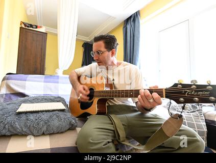 (220522) -- TIANJIN, 22. Mai 2022 (Xinhua) -- Iarroumets Jonathan spielt zu Hause Gitarre, nachdem er freiwillig in einer Gemeinde im Bezirk Nankai, Tianjin, Nordchina, gearbeitet hat, 22. Mai 2022. Die nordchinesische Gemeinde Tianjin erlebte kürzlich ein Wiederaufleben des COVID-19. Iarroumets Jonathan, ein Belgier, der seit einem Jahrzehnt in Tianjin lebt, meldete sich als Freiwilliger in seiner Wohngemeinde an. Jonathan entwickelte schon in jungen Jahren eine tiefe Vorliebe für die chinesische Kultur und kam nach seinem College-Abschluss nach China, um dort zu leben. Tianjin ist seine zweite Heimatstadt geworden. „Jeder ist damit beschäftigt, die Pandemie zu bekämpfen. I w Stockfoto