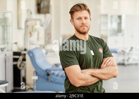 Waist-up-Porträt eines stolzen Blutspenders, der im med-Spendenzentrum mit dem Aufkleber „Leben retten“ auf der Brust steht und auf die Kamera schaut, Platz kopieren Stockfoto