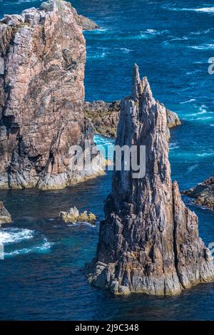 Felsaufschlüsse ragen aus dem strahlend blauen Meer. Stockfoto