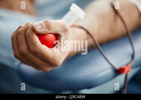 Nahaufnahme eines jungen Mannes, der Blut spendet und die rote Kugel in der Hand hält, Platz kopieren Stockfoto