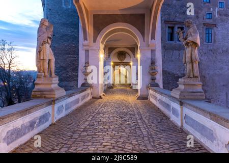 VEW der überdachten Brücke mit Statuen in Cesky Krumlov Schloss im Sonnenaufgang. Tschechische Republik. Stockfoto