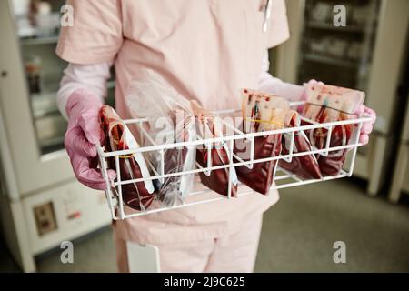Nahaufnahme einer nicht erkennbaren Krankenschwester, die ein Tablett mit Blutbeuteln im Spendenzentrum oder in der Klinik hält, Platz zum Kopieren Stockfoto