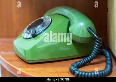 Grünes Vintage-Telefon mit drehbarem Zifferblatt. Das Telefon im Regal Stockfoto