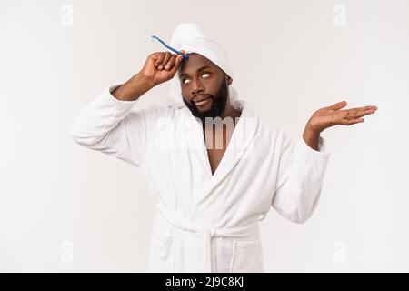 Porträt eines glücklichen jungen dunklen anm, der seine Zähne mit schwarzer Zahnpasta auf weißem Hintergrund putzt. Stockfoto