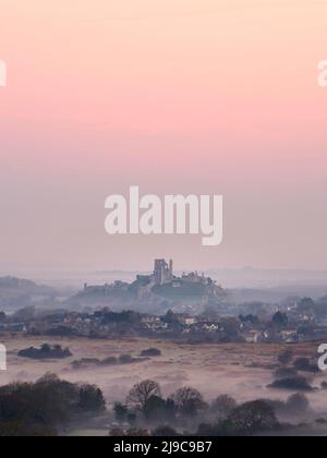 Corfe Castle mit Blick auf Corfe Castle Dorf an einem nebligen Morgen. Stockfoto