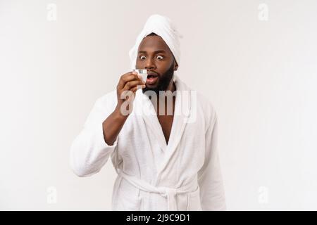 Lächelnder afroamerikanischer Mann, der Creme auf sein Gesicht applyte. Hautpflegekonzept des Mannes Stockfoto