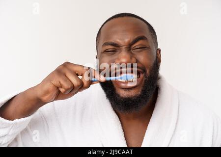 Porträt eines glücklichen jungen dunklen anm, der seine Zähne mit schwarzer Zahnpasta auf weißem Hintergrund putzt. Stockfoto