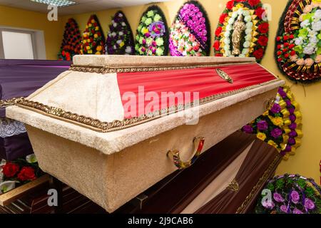 Innenraum des Raumes mit Bestattungszubehör. Geschäft mit Särgen, Beerdigungskränzen und Blumen. Stockfoto