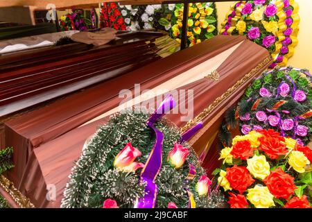 Innenraum des Raumes mit Bestattungszubehör. Geschäft mit Särgen, Beerdigungskränzen und Blumen. Stockfoto