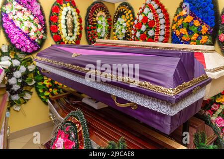 Innenraum des Raumes mit Bestattungszubehör. Geschäft mit Särgen, Beerdigungskränzen und Blumen. Stockfoto