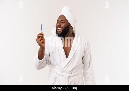 Porträt eines glücklichen jungen dunklen anm, der seine Zähne mit schwarzer Zahnpasta auf weißem Hintergrund putzt. Stockfoto