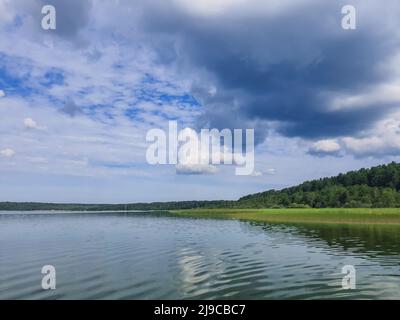 Neblige Meereslandschaft - die ruhige Wasseroberfläche des Sees spiegelt den Fliederhimmel mit rosa und blauen Wolken nach Sonnenuntergang wider. Stockfoto