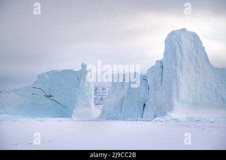 Riesige Eisberge ragen über dem Meereis im Uummannaq-Fjord im Nordwesten Grönlands. Stockfoto