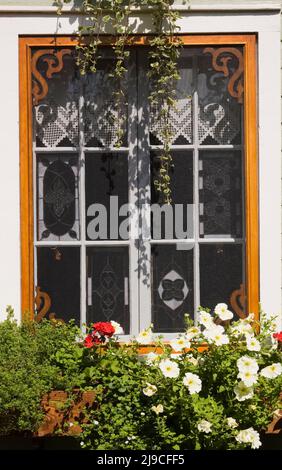 Dekoriertes Glasfenster an der Seite eines alten, ca. 1900 Jahre alten, im kanadischen Cottage-Stil gehaltenen Hauses im Sommer. Stockfoto