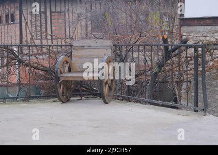 Kleiner Holzstuhl und Räder, Rollstuhl aus Stein. Stockfoto