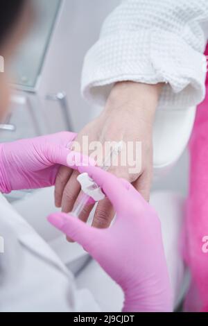 Beauty-Arzt macht Anti-Aging-Injektion in den Arm für männliche Client Stockfoto