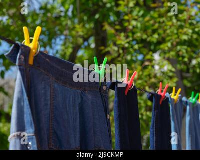 Denim-Kleidung, die an einer Wäscheleine hängt. Nahaufnahme. Stockfoto