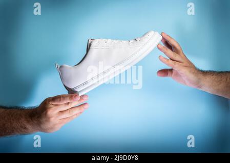 Belgrad, Serbien - 11. Mai 2022. Hände, die New Camper Sneaker oder Tennisschuhe auf blauem Hintergrund halten. Neue Turnschuhe oder Sportschuhe ohne Marke – Herren-Spor Stockfoto