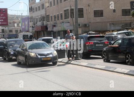 Nablus, Palästina. 12.. Mai 2022. Ein israelischer Siedler entfernt die palästinensische Flagge, die auf der Straße in der Mitte des Marktes in der Stadt Hawara, südlich von Nablus im Westjordanland, hängt. (Foto von Nasser Ishtayeh/SOPA Images/Sipa USA) Quelle: SIPA USA/Alamy Live News Stockfoto