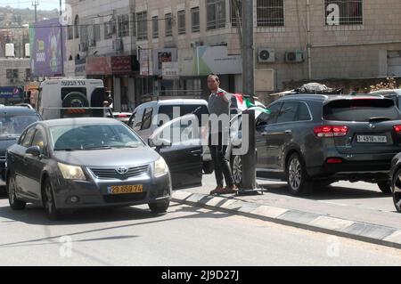 Nablus, Palästina. 12.. Mai 2022. Ein israelischer Siedler entfernt die palästinensische Flagge, die auf der Straße in der Mitte des Marktes in der Stadt Hawara, südlich von Nablus im Westjordanland, hängt. (Bild: © Nasser Ishtayeh/SOPA Images via ZUMA Press Wire) Stockfoto