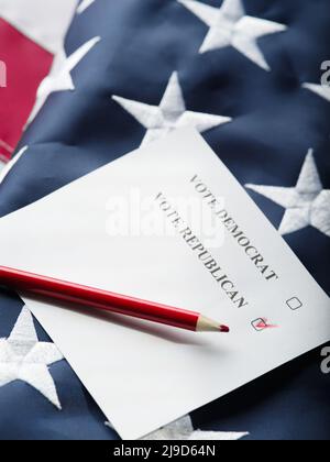 Stimmzettel mit republikanischen und demokratischen Kandidaten und einem roten Bleistift vor dem Hintergrund der amerikanischen Nationalflagge. Nahaufnahme. Wahlen, Abstimmungen Stockfoto