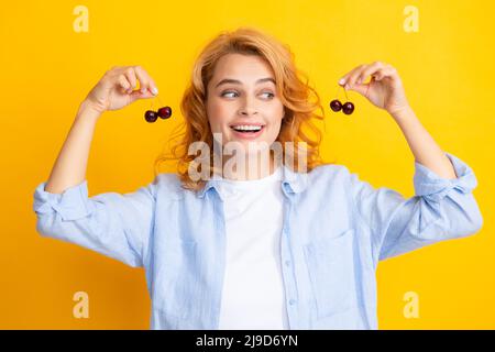 Porträt einer Frau mit Kirschen auf gelbem Studio isolierten Hintergrund. Stockfoto
