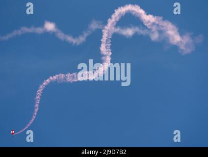 Ein Mitglied des Fallschirmteams der kanadischen Streitkräfte, die Skyhawks, geht in einem Muster namens Candy Cane über Victoria, British Columb, dem roten Rauch nach Stockfoto