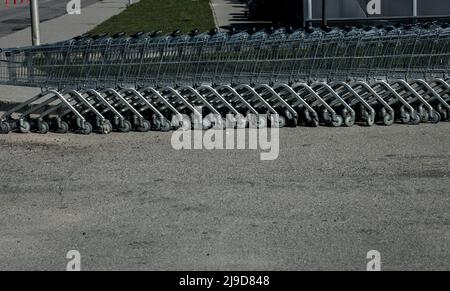 Viele Metallwagen auf dem Asphalt. Konzept des Shoppings. Stockfoto