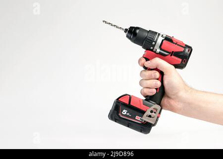 Akku-Bohrmaschine in schwarz und rot. Schraubendreher mit Bohrer in der Hand auf weißem Hintergrund. Moderne Schreinerei Werkzeug. Stockfoto