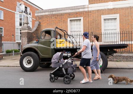 Ein Paar Männer und Frauen schieben einen Kinderwagen neben einen geparkten Austin Army Water Truck Military Green in Greenwich London, England Stockfoto