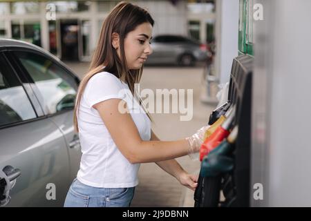 Frau bereitet sich auf das Betanken an der Tankstelle vor. Weibliche Hand Füllen Benzin Benzin Kraftstoff im Auto. Konzept der Benzinpreise. Self-Service. Kraftstoffmangel Stockfoto