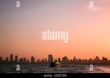 Blick auf den Sonnenaufgang am Flussufer auf die Skyline von Belém do Pará, der Metropole des brasilianischen Amazonas, mit einem kleinen Fährschiff im Vordergrund. Juli 2008. Stockfoto