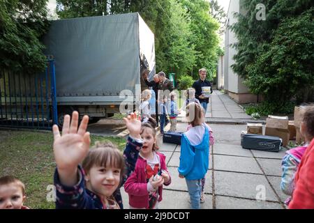 Lviv, Ukraine. 17.. Mai 2022. Waisenkinder und Flüchtlingskinder in der Ukraine vermischen sich, während Freiwillige von Veteranen in der Hilfe benötigte Vorräte und Süße für sie abliefern. Sie stehen auf dem Gelände ihres Kinderheims in Lemberg, in dem derzeit einige Flüchtlingskinder untergebracht sind, die mit ihren Eltern aus vom Krieg zerrissenen Städten in der Ukraine hierher gekommen sind, sowie Jungen und Mädchen, die vor der brutalen russischen Invasion und wegen dieser elterlos wurden. (Bild: © Amy Katz/ZUMA Press Wire) Stockfoto