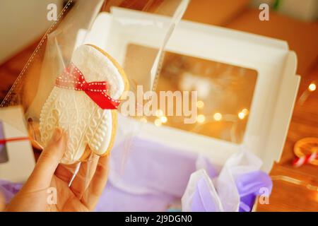 Die Hand der Frau hält WeihnachtsLebkuchen in Form von Fäustling. Stockfoto