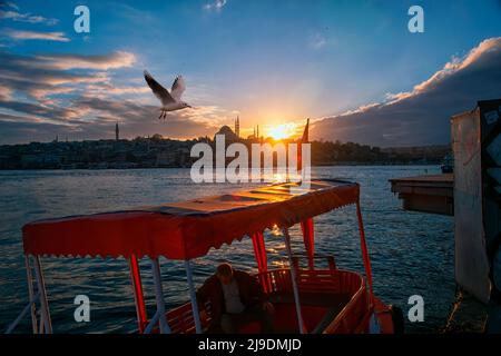 Istanbul, Türkei - November 23 2018: Passagierboot und wunderbarer Sonnenuntergang in Istanbul. Der Mann auf dem Passagierboot und die Möwe, die in der Luft schweben Stockfoto