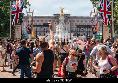 Tourist fotografiert die Union Jack-Flaggen, die von der Mall bis zum Buckingham Palace vor dem Platinum Jubilee der Königin gehangen wurden Stockfoto