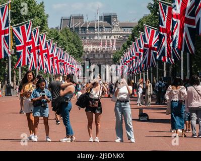 Tourist fotografiert die Union Jack-Flaggen, die von der Mall bis zum Buckingham Palace vor dem Platinum Jubilee der Königin gehangen wurden Stockfoto