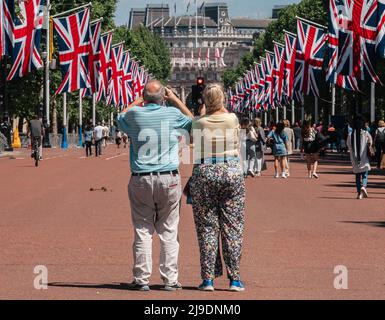 Tourist fotografiert die Union Jack-Flaggen, die von der Mall bis zum Buckingham Palace vor dem Platinum Jubilee der Königin gehangen wurden Stockfoto