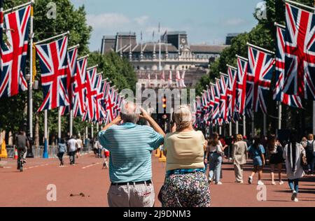 Tourist fotografiert die Union Jack-Flaggen, die von der Mall bis zum Buckingham Palace vor dem Platinum Jubilee der Königin gehangen wurden Stockfoto