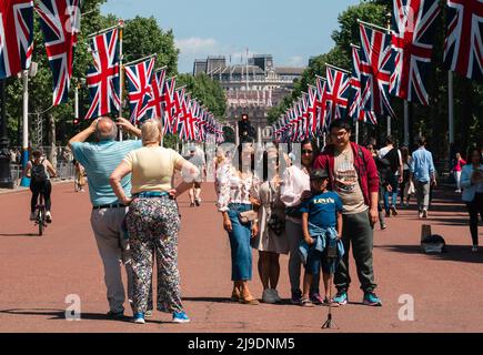 Tourist fotografiert die Union Jack-Flaggen, die von der Mall bis zum Buckingham Palace vor dem Platinum Jubilee der Königin gehangen wurden Stockfoto