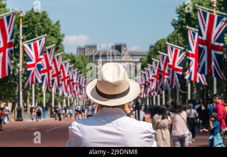 Tourist fotografiert die Union Jack-Flaggen, die von der Mall bis zum Buckingham Palace vor dem Platinum Jubilee der Königin gehangen wurden Stockfoto