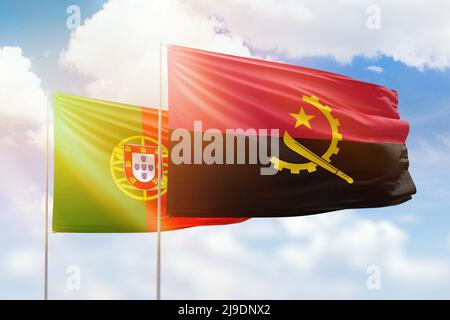 Sonniger blauer Himmel und Flaggen von angola und portugal Stockfoto