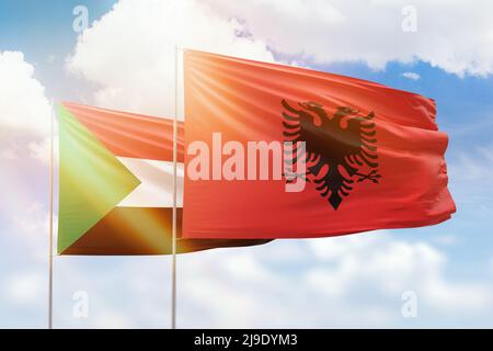 Sonniger blauer Himmel und Flaggen von albanien und sudan Stockfoto