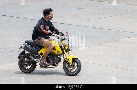 SAMUT PRAKAN, THAILAND, APR 02 2022, Ein Mann mit Gesichtsmaske fährt ein Motorrad Stockfoto