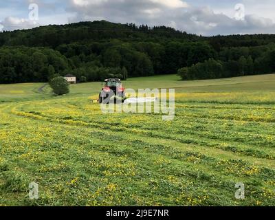 PRODUKTION - 21. Mai 2022, Bayern, Ahorntal: Ein Landwirt schneidet Gras mit einem Frontmäher und einem Heckmäher. Das Gras wird zur Viehfütterung in Silage umgewandelt. (Zu dpa: „Kuhglocke oder Mäher? Wie klingt und riecht Bayern?') Foto: Kathrin Zeilmann/dpa Stockfoto