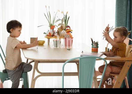Kinder haben Spaß zu Hause am Tisch, die Schaffung von handgefertigten Kunst. Kinder zeichnen und kommunizieren in der Küche, emotionaler Intellekt Stockfoto