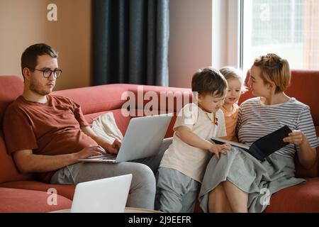 Große glückliche Familie, die Filme und Spiele auf einem Laptop ansieht. Mutter Vater Kinder verbringen Zeit mit Gadgets auf dem Sofa Kinder mit Eltern suchen auf Stockfoto