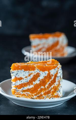 Stück zarte Karotten-Quark-Torte mit Mohn, Honig und Orangensaft auf dem Teller, Nahaufnahme. Kuchen ohne Backen Stockfoto